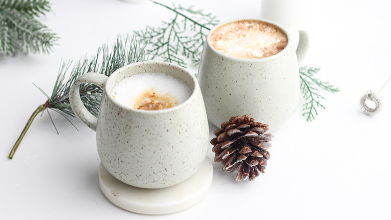 Two mugs of foam-topped coffee drinks