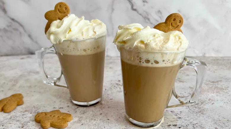 Glass mugs of coffee lattes with gingerbread men