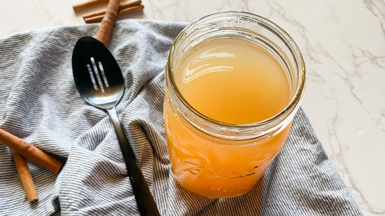 Mason jar of cider with spoon and cinnamon sticks