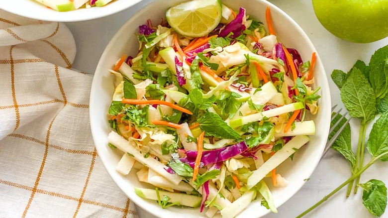 Slaw salad with sliced apple and mint leaves. 