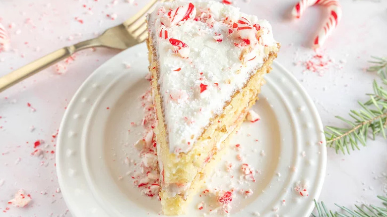 Yellow cake slice with white frosting and peppermint candies.