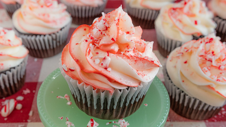 Chocolate cupcake with white and red frosting and mint crumbles.