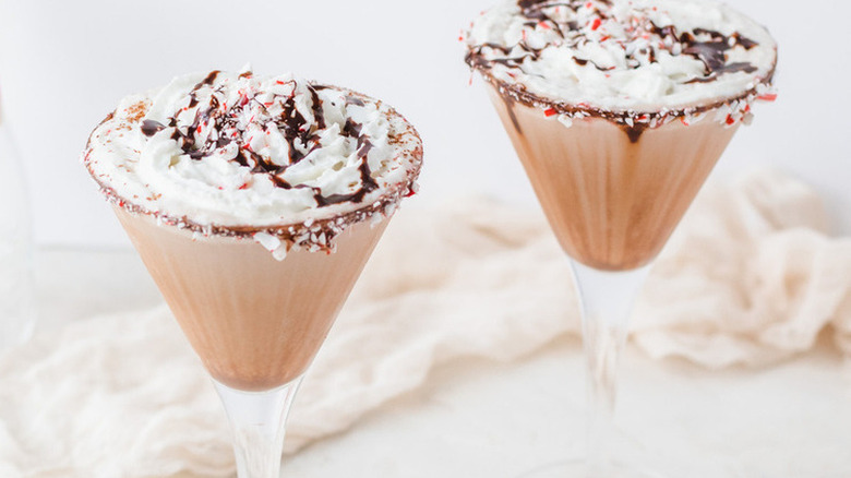 Two cocktail glasses with creamy chocolate drinks and crushed candies.