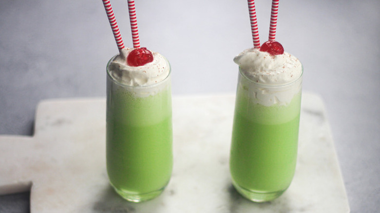 Tall glasses with green milkshakes, whipped cream, and cherries.