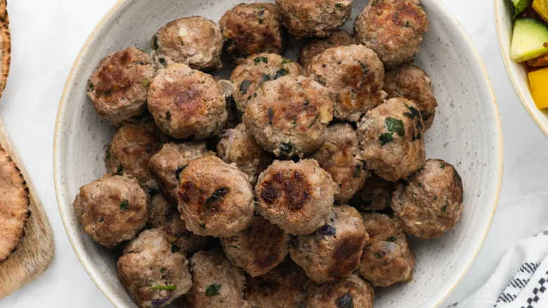 Platter of browned meatballs with green flecks.