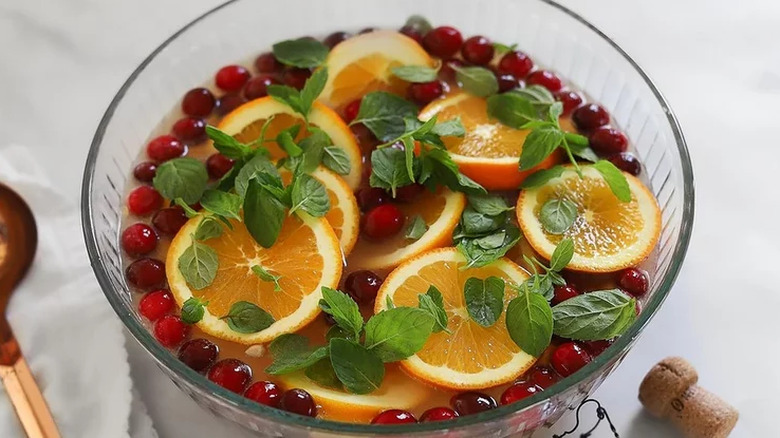 Punch bowl with cranberries, orange slices, and mint leaves.