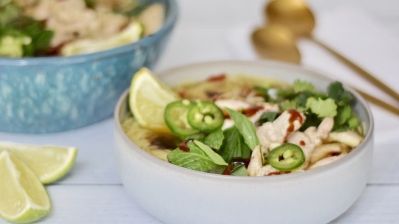 Bowls of pho noodles, peppers, mint leaves, and chicken.