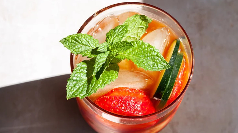 Cocktail with mint, ice, strawberries, and cucumbers.