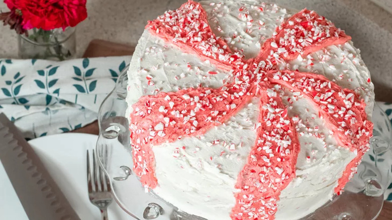 Round cake with white and pink striped frosting and candies.