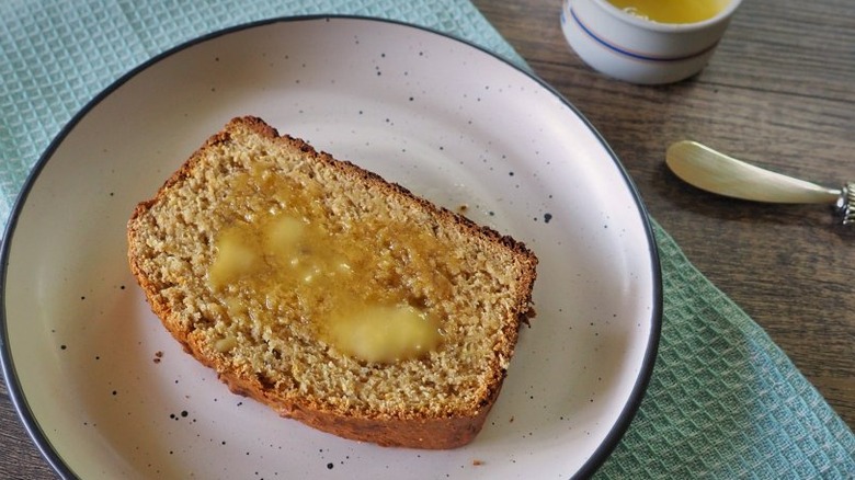 Sliced of buttered banana bread on a plate.