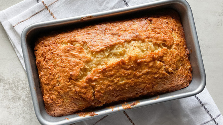 Baked loaf of golden brown bread in a pan.