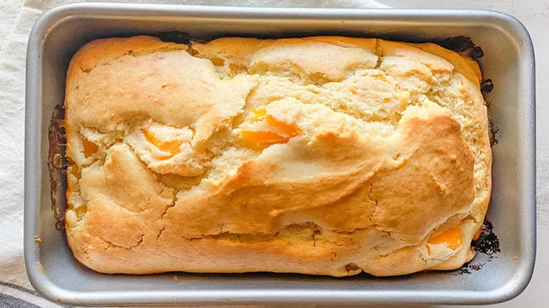 Baked quick bread with peach chunks in loaf pan. 