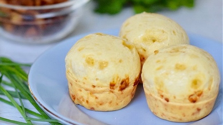 Muffin-sized cheese breads on white plate. 