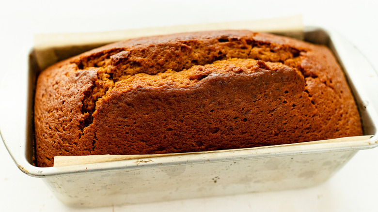 Loaf of baked pumpkin bread in a metal bread pan. 