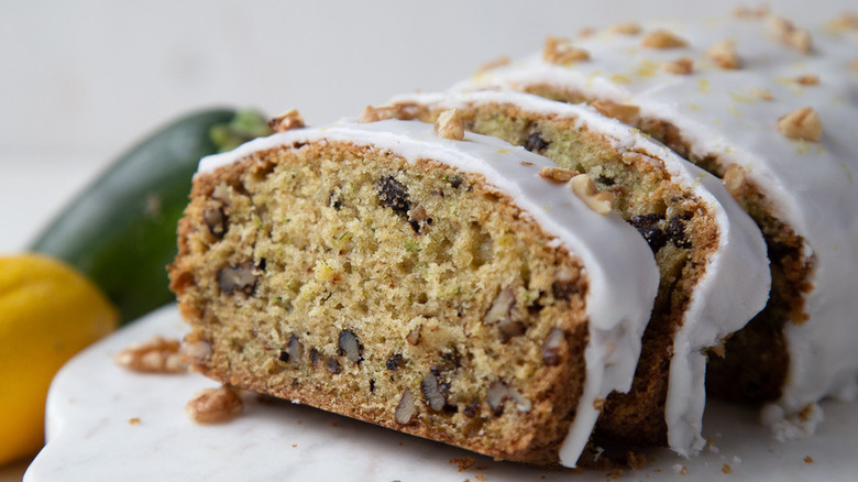 Quick bread slices with walnuts and thick white icing. 