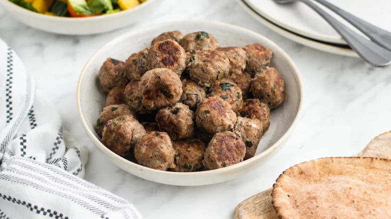 Meatballs in a bowl with salad and pita bread