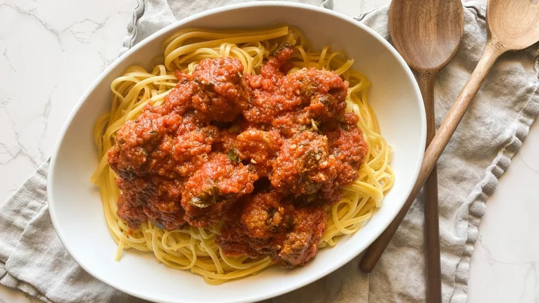 Spaghetti in sauce with meatballs and serving utensils