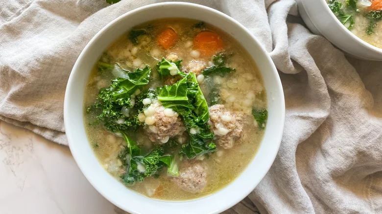 Bowls of meatball soup with kale and couscous