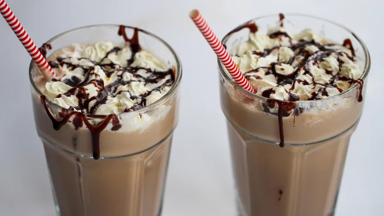 Two chocolate milkshakes with striped straws