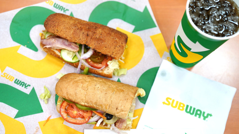 Two Subway sandwiches sitting on a table