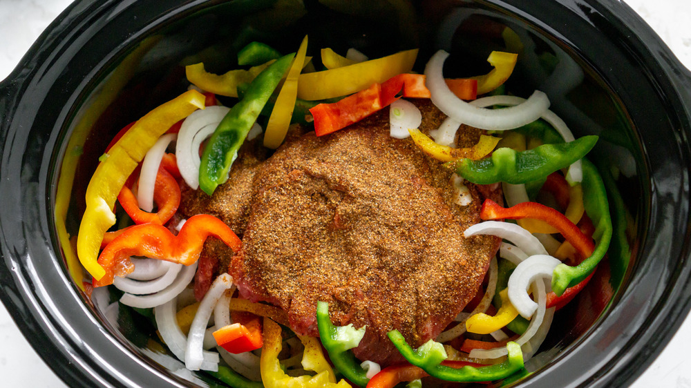 peppers, onions and seasoned steak in slow cooker