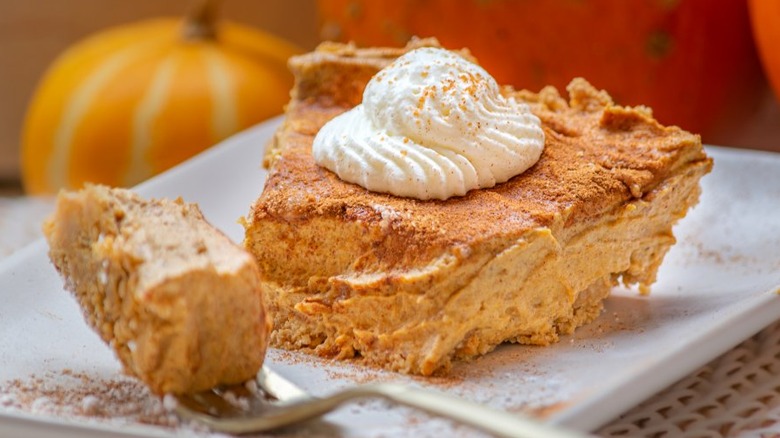 Slice of no-bake pumpkin pie with whipped cream and a fork.