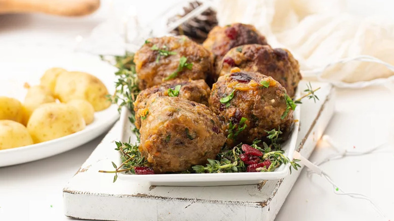 Meatballs on platter with herbs and dried cranberries.