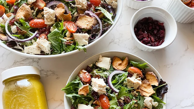 Bowls of salad with chicken, tomato, and red onion.