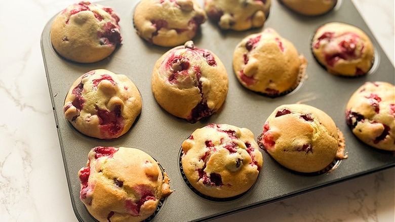 Muffin pan with baked cranberry muffins.