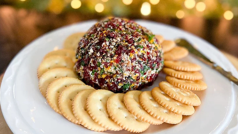 Red and green cheese ball with ring of crackers.