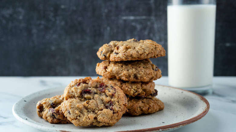 Stacked cranberry oatmeal cookies with glass of milk.