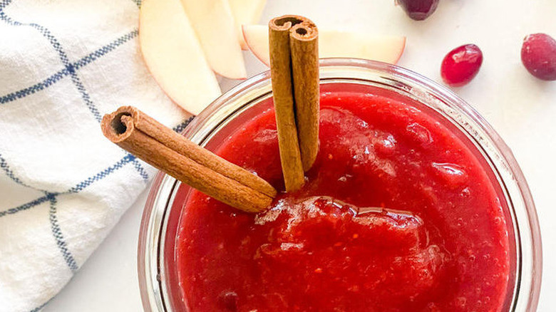 Red cranberry applesauce with cinnamon sticks.