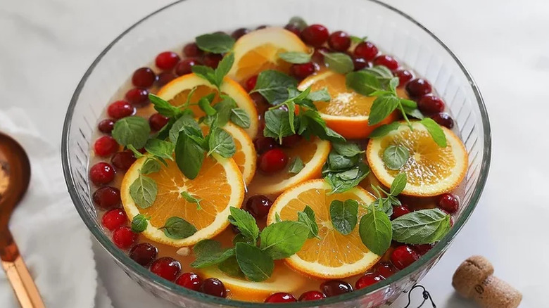 Punch with cranberries, orange, and mint in glass bowl.