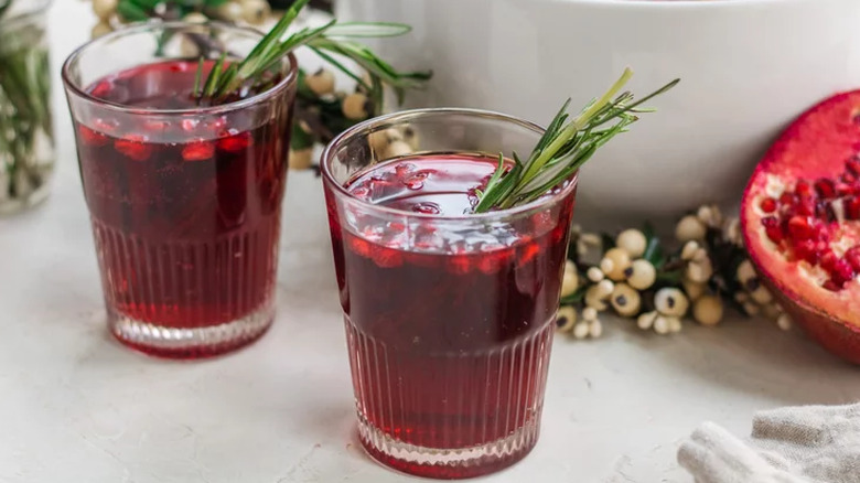 Glasses of cranberry-pomegranate punch with rosemary sprigs.