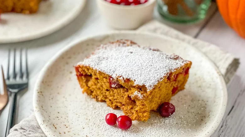 Pumpkin cake on plate with whole cranberries.