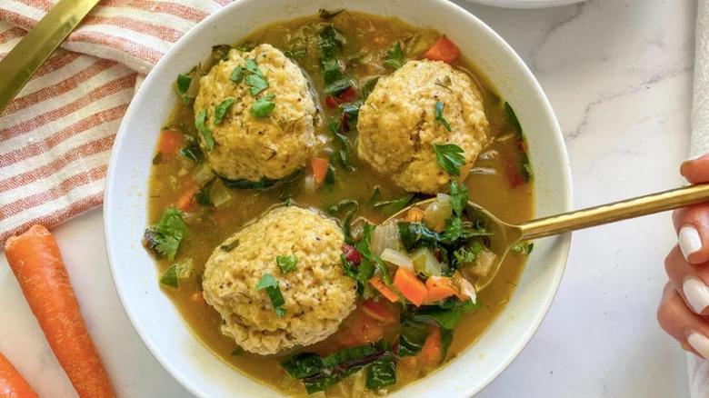 hand spooning matzo ball soup