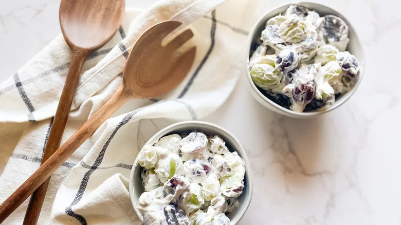 bowls of creamy grape salad with wooden utensils 