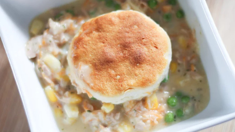 Creamy tuna casserole in dish topped with round biscuit.