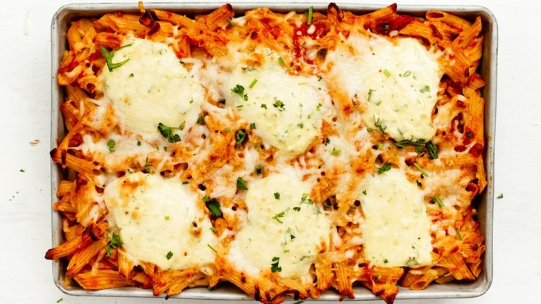 Pan of baked pasta with tomato sauce and cheese dollops.