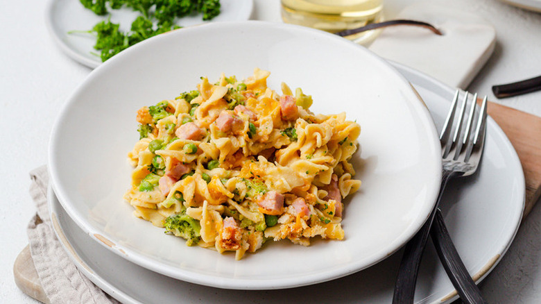 White plate with ham, broccoli, and noodle mixture.