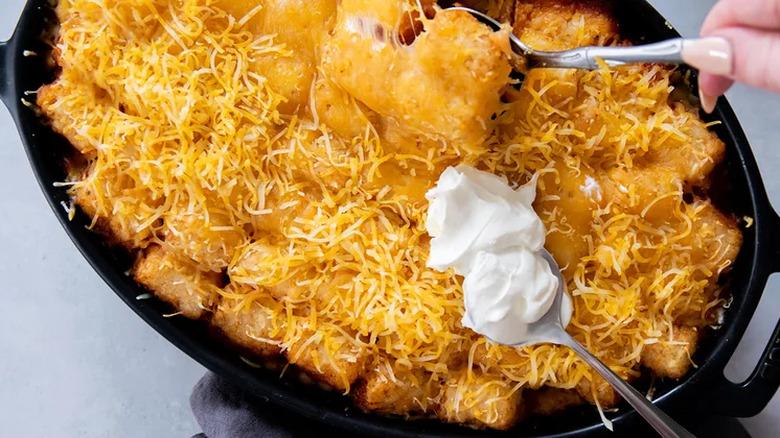 Oval baking dish with baked tater tots and cheese.