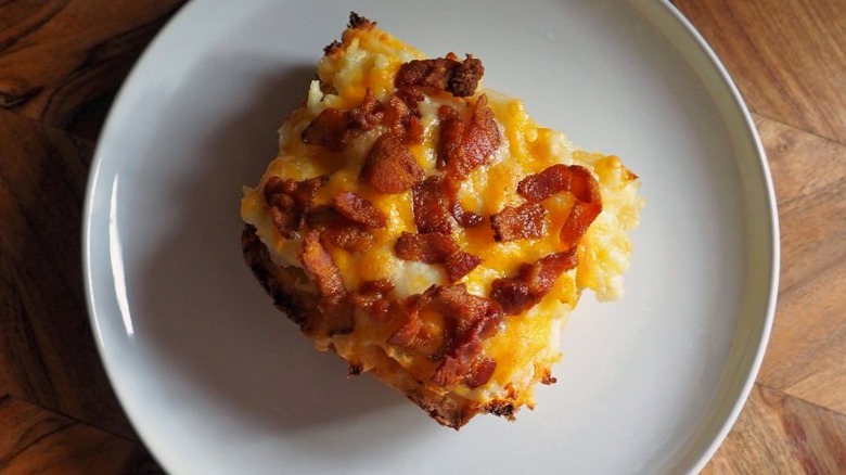 Slice of egg bake casserole with bacon and cheese topping.