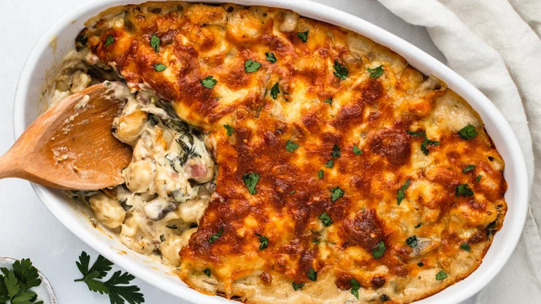 Baked gnocchi and cream sauce in oval baking dish.