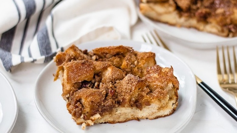 Slice of baked bread cube and cinnamon casserole on white plate.