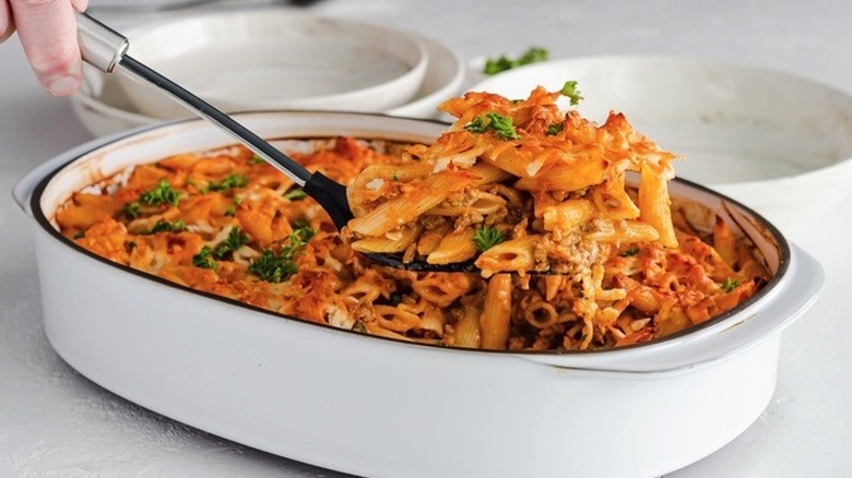 White baking dish with baked pasta, ground meat, and sauce.