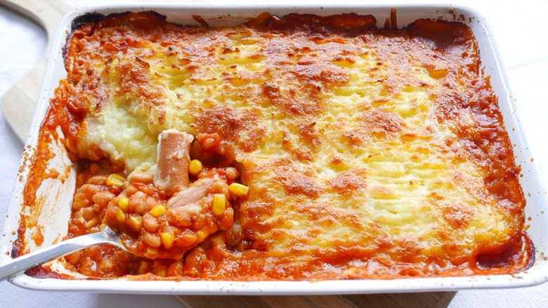 Beans, corn, potatoes, and hot dogs baked in a casserole dish.