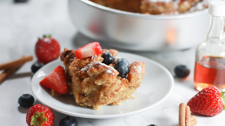 Slice of bread pudding on plate with fresh berries.