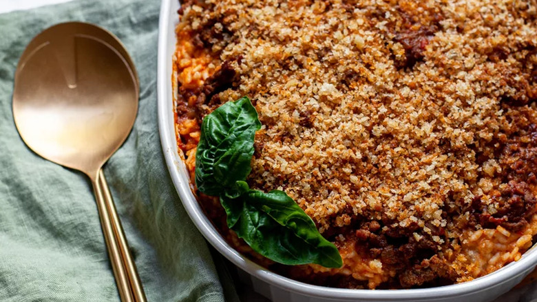 Baked rice, beef, and sauce in an oval casserole dish.