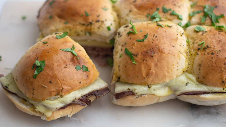 Baked beef and cheese sliders with one pulled away.