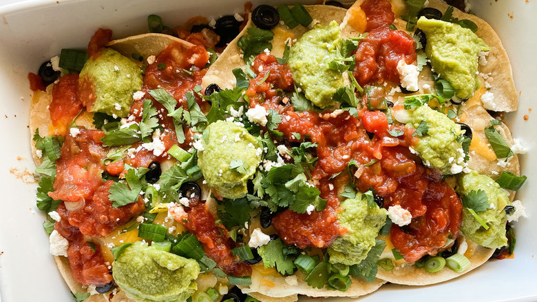 Baked casserole of tortillas, salsa, beef, olives, and guacamole.